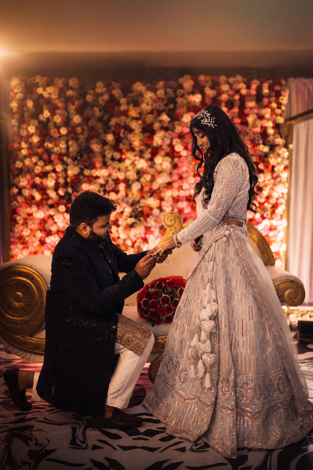 The Lucknow engagement — Abishek on one knee against a wall of roses
