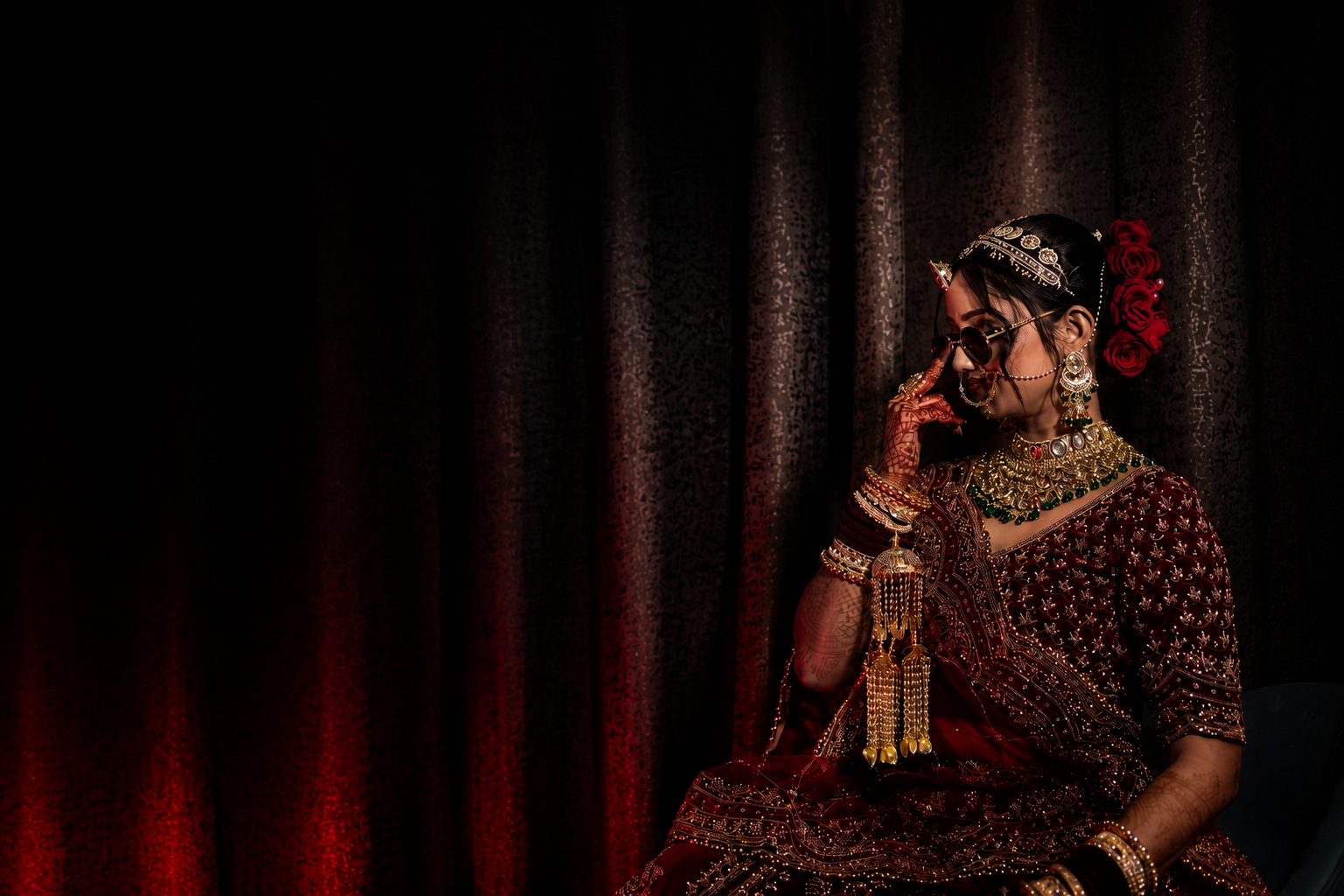 A cinematic pause — Vaishnavi against a deep red curtain, sunglasses lowered