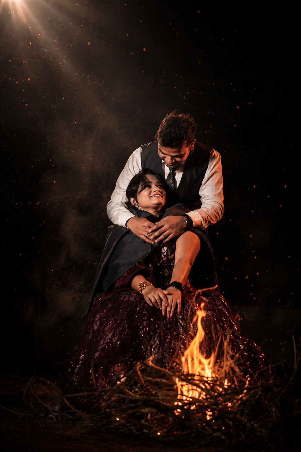 Sarita & Dharmendra — Sarita and Dharmendra beside a bonfire at night, embers rising around them