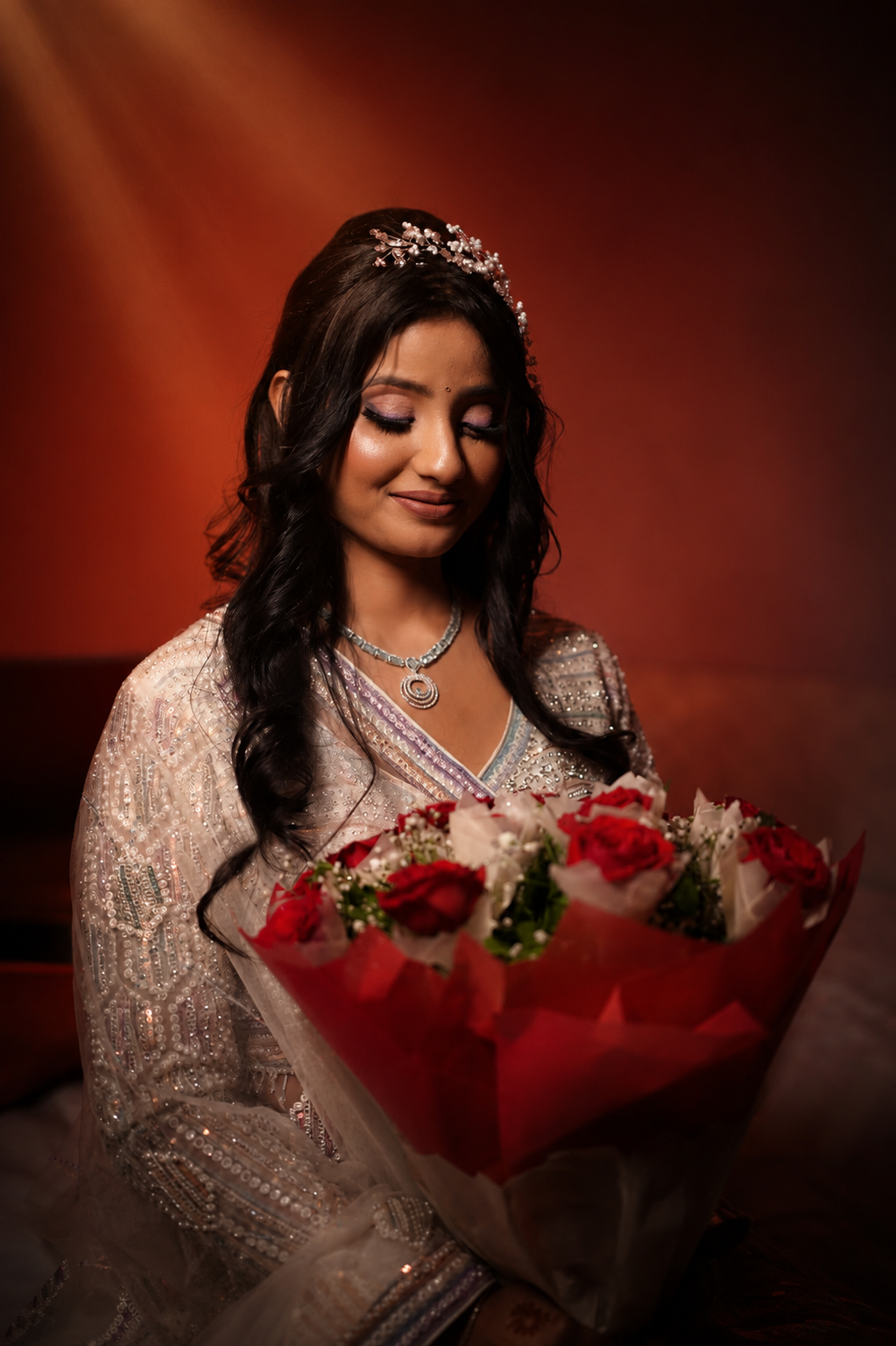 A quiet close — Vaishnavi with a bouquet of red roses, eyes lowered, tiara catching the light
