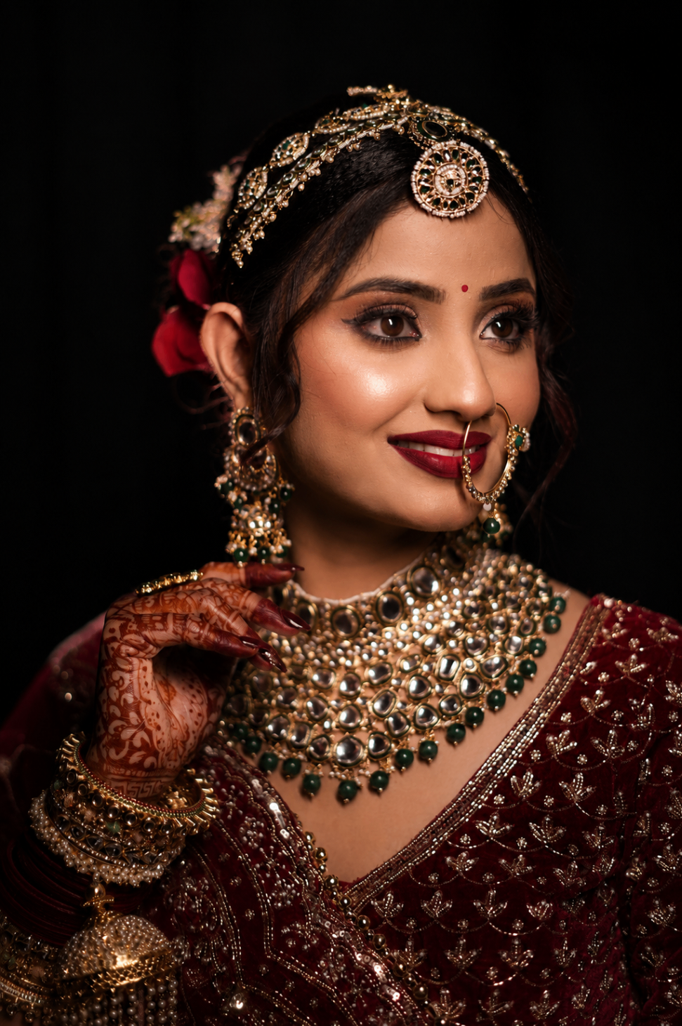 Bridal portrait — Vaishnavi in emerald kundan and maroon velvet, a red rose in her hair