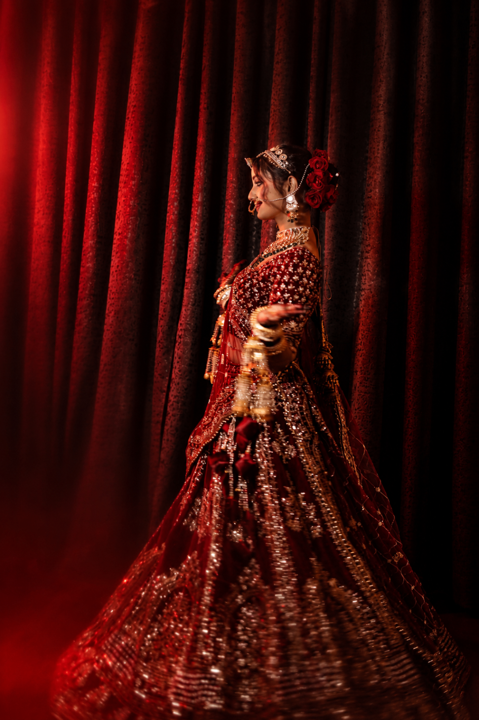 The lehenga twirl — crimson velvet and gold catching a single beam of light